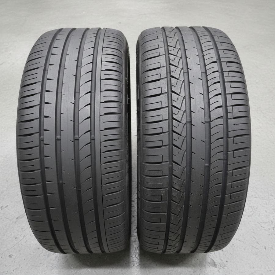 Two performance tires side by side on a garage floor showing different tread patterns